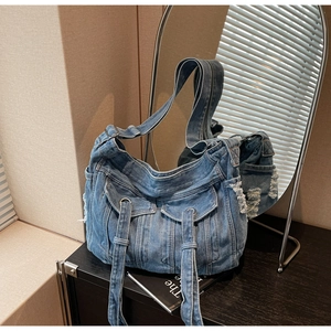 Detail of vintage denim crossbody bag featuring multiple flap pockets and metal eyelets