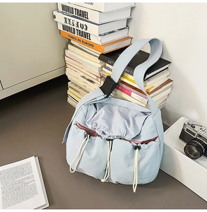 Detail of light blue crossbody bag with drawstring pockets and quick-release buckle strap