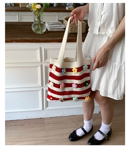 Detailed view of handmade striped knit tote bag with vibrant 3D crochet floral embellishments