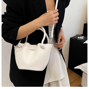 White litchi pattern bucket bag with knot handle shown as a crossbody on a model