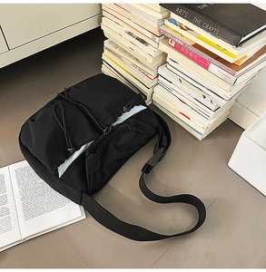 Detail of black pleated nylon crossbody bag with drawstring closure and wide strap