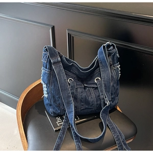 Detail of vintage denim crossbody bag featuring distressed frayed edges and silver hardware