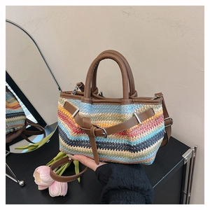 Detail view of woven straw beach bag with rainbow stripes and brown leather trim accents
