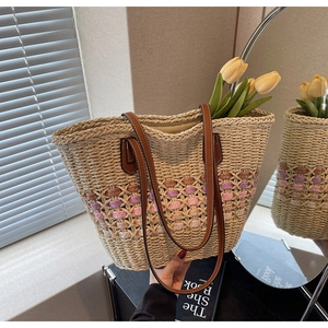 Détail d'un sac cabas en paille avec motifs roses, anses en cuir et tulipes à l'intérieur