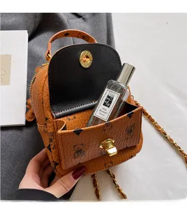 Detailansicht der orangefarbenen Mini-Beuteltasche mit Kieseltextur und goldener Kette