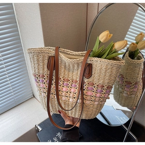 Détail du sac cabas en paille tissé à la main avec rayures colorées et anses en cuir brun