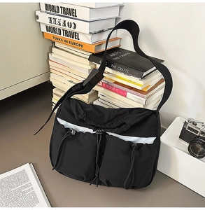 Detail of black utilitarian crossbody bag with drawstring closure and outer pockets