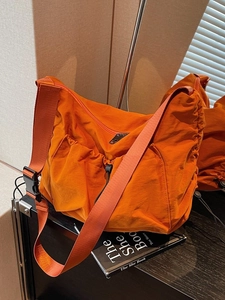 Large orange nylon crossbody dumpling bag with drawstring and wide strap design