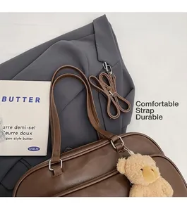 Close-up of large brown Boston bag with shoulder strap and plush bear charm detail