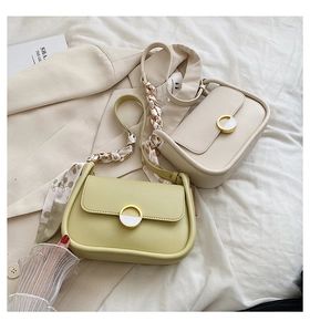 Détail de sacs bandoulière en cuir mat vert avocat et crème avec poignées en foulard