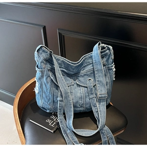 Detail of vintage blue denim hobo bag featuring cargo pockets and frayed edge design