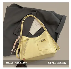 Detail of pale yellow tote with crocodile texture, metal zipper and woven charm