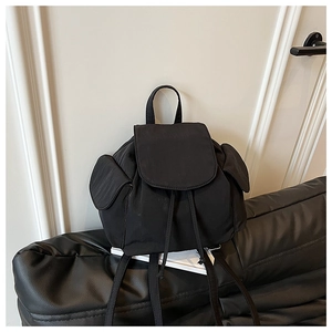 Detail view of small black nylon backpack with drawstring closure and side flap pockets
