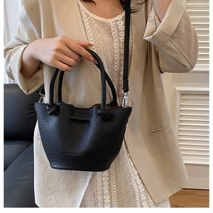 Lifestyle shot of black lychee leather bucket bag with silver hardware on a model