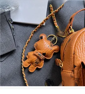 Detail eines braunen Lederbärenanhängers und Rucksacks mit goldener Kette als Accessoire