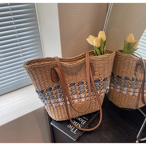 Détail du sac cabas en paille avec motifs bleus et anses en cuir marron