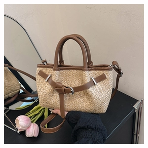 Detail of woven straw tote bag with brown leather trim and detachable shoulder strap