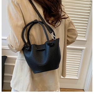 Detailed view of black lychee grain leather bucket bag with silver handles and strap