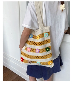 Detailed macro view of 3D crochet flowers on striped knit oversized shoulder tote bag