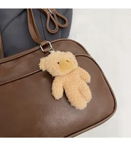 Close-up of brown Boston bag featuring CHERIMATE logo and a cute plush bear pendant