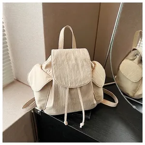Detail of cream canvas backpack featuring drawstring closure and textured fabric