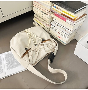 Detail of cream drawstring crossbody bag with brown lining and adjustable wide strap