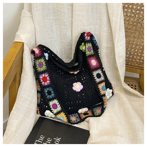 Detail der bunten handgehäkelten Blumenmuster auf schwarzer gestrickter Hobo-Tasche