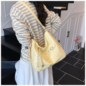 Detail of light yellow hobo bag with crocodile embossed texture and metal buckle pocket