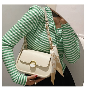 Détail du sac selle crème avec une boucle ronde et un foulard en soie décoratif
