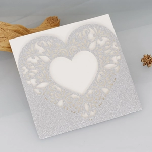 Close-up of laser-cut heart invitation with silver glitter finish and white inner card