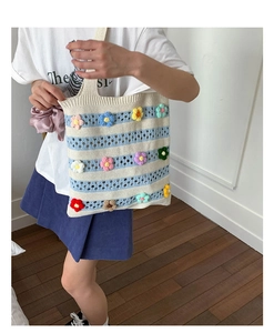Detailed knit texture of a striped tote bag featuring 3D crochet flowers in vibrant colors