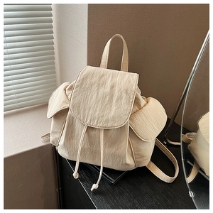 Detailed view of cream canvas backpack with drawstring closure and side flap pockets