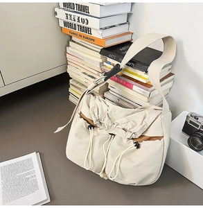 Detail of off-white nylon crossbody bag featuring drawstring pockets and wide strap