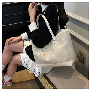 Close-up of cream floral jacquard tote bag with elegant white leather trim and FLOR charm
