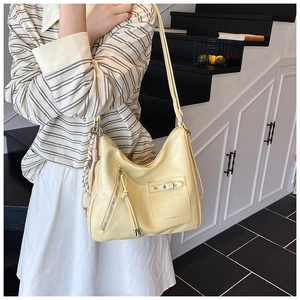 Detail of cream crocodile embossed tote bag with tassels and buckle pocket on model