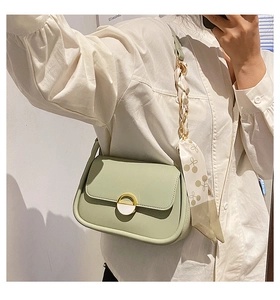 Détail du sac selle vert clair avec boucle anneau dorée et ruban en soie imprimé cerise