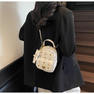 Nahaufnahme des cremefarbenen Mini-Rucksacks mit Bärenprint und Hasenanhänger auf Treppen