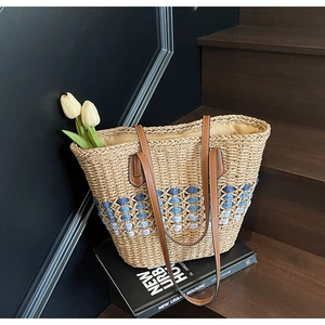 Détail d'un sac cabas en paille tissé main avec motifs dégradés et anses en cuir