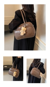 Detail of vintage brown leather pillow bag with plush bear charm and zip pocket