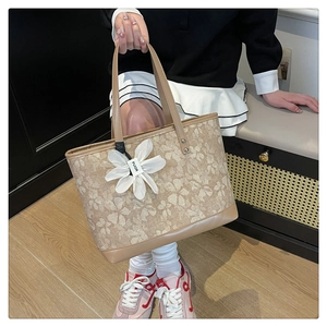 Close-up of light brown floral tote bag featuring a decorative white fabric flower charm