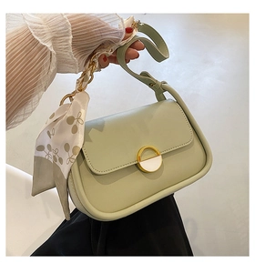 Détail du sac selle vert menthe avec boucle dorée et foulard en soie sur la bandoulière