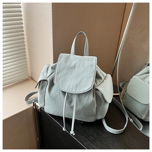 Detail of mint green canvas backpack with drawstring closure and flap cover design