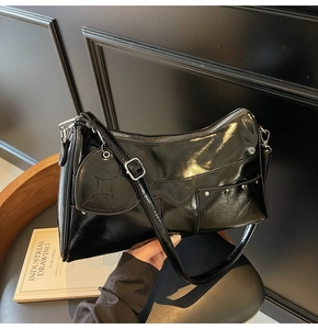 Top-down view of black patent leather tote bag with heart charm and silver rivets