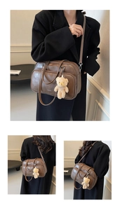 Detailed view of brown PU leather Boston bag with plush bear charm and multiple zip pockets