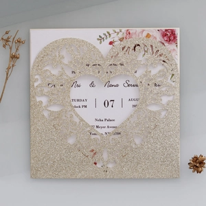 Detail view of laser-cut glitter gold heart invitation with pink floral inner card