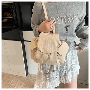 Detail of cream drawstring canvas backpack featuring side pockets and textured fabric finish