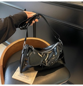 Detail of black patent leather shoulder bag with silver studs and heart-shaped charm