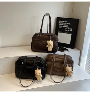 Detailed view of three large Boston bags in brown and black with bear charms