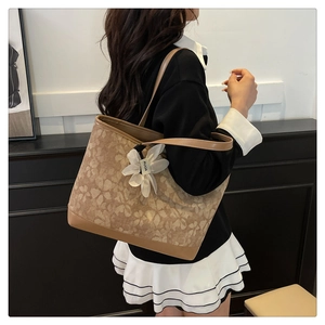 Model view of large caramel floral tote bag with a white flower pendant and PU leather finish