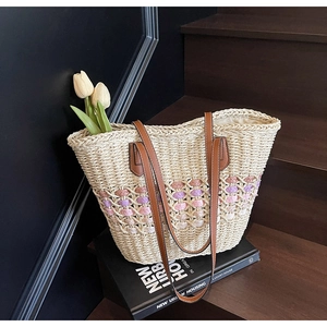 Détail d'un sac cabas en paille tressée avec accents colorés et anses en cuir